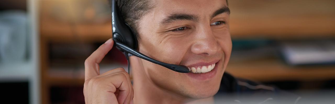 Un homme aux cheveux noirs, souriant, téléphone avec une oreillette